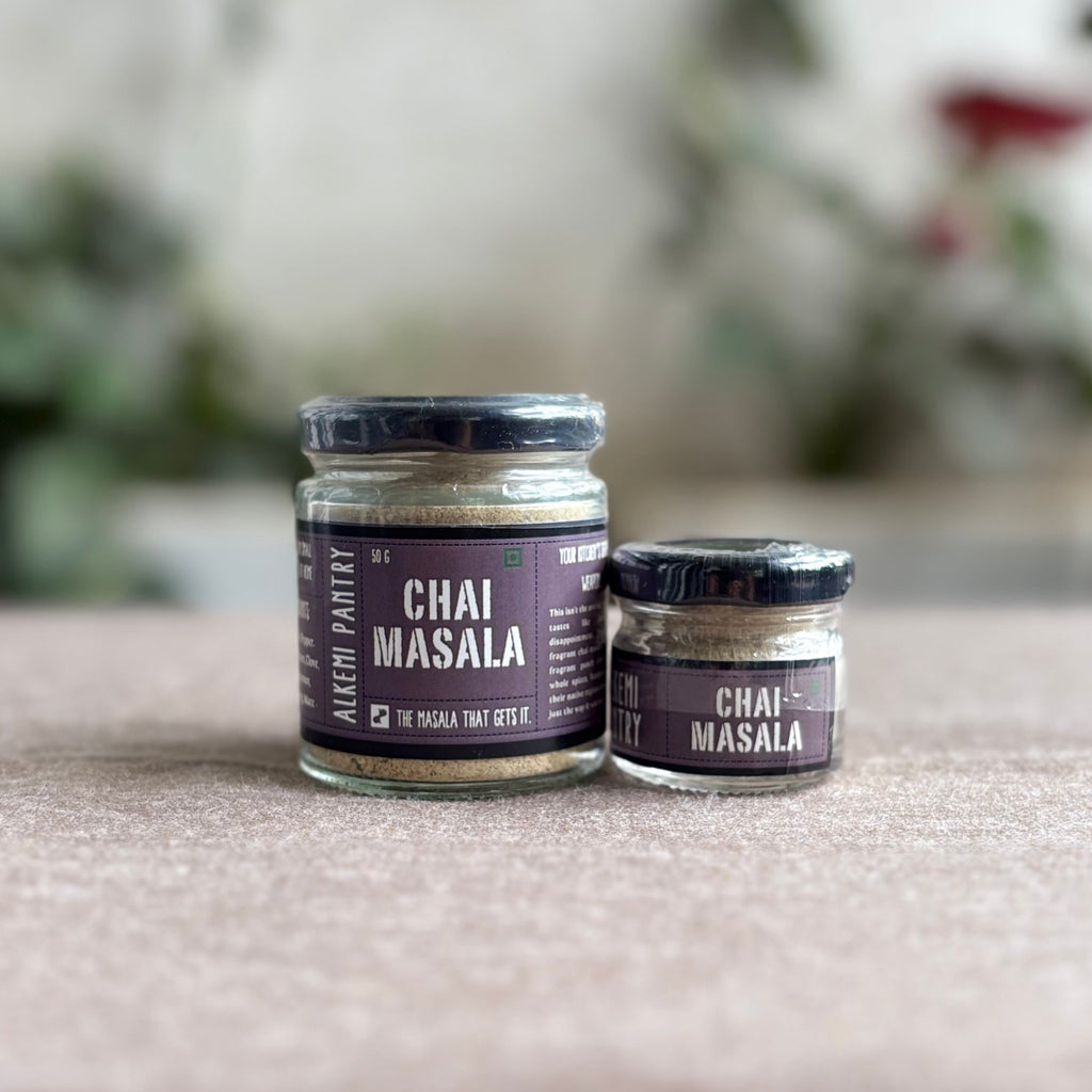 Two jars of Chai Masala on a textured surface with a blurred natural background