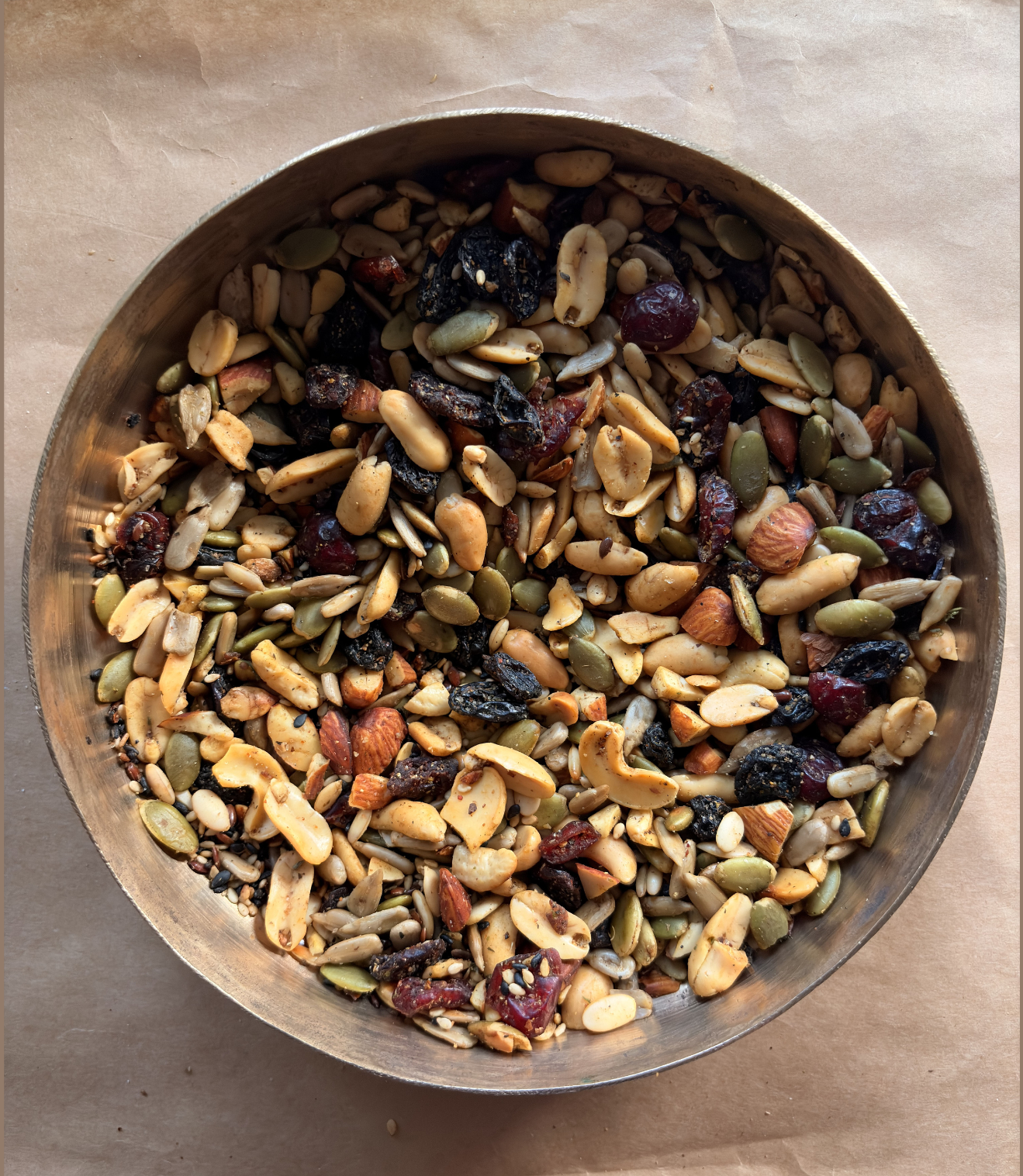 Metal bowl filled with a mix of nuts and dried fruits and pumpkin seeds and sunflower seeds for healthy snacking
