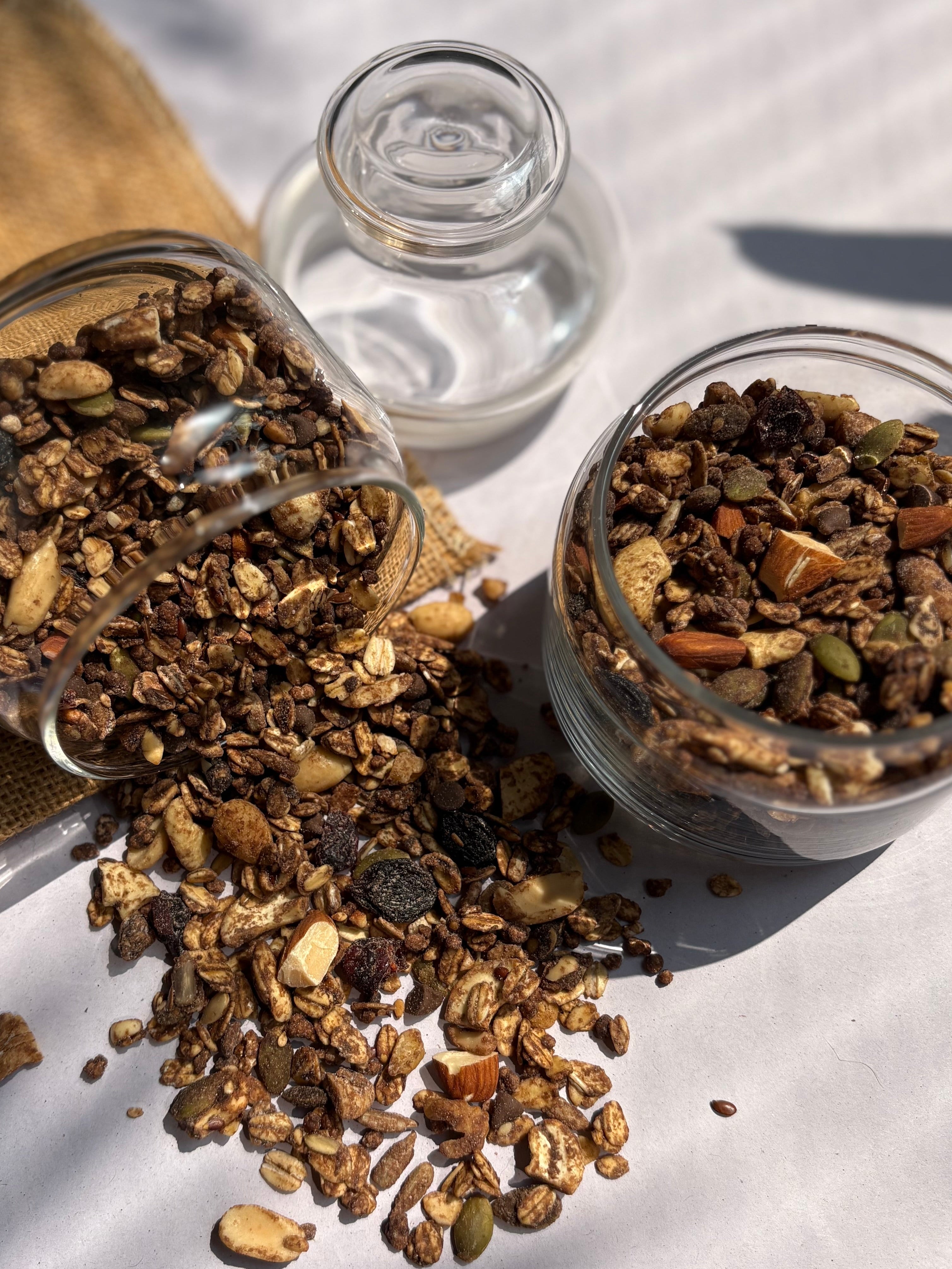 Two glass jars with granola on a textured surface