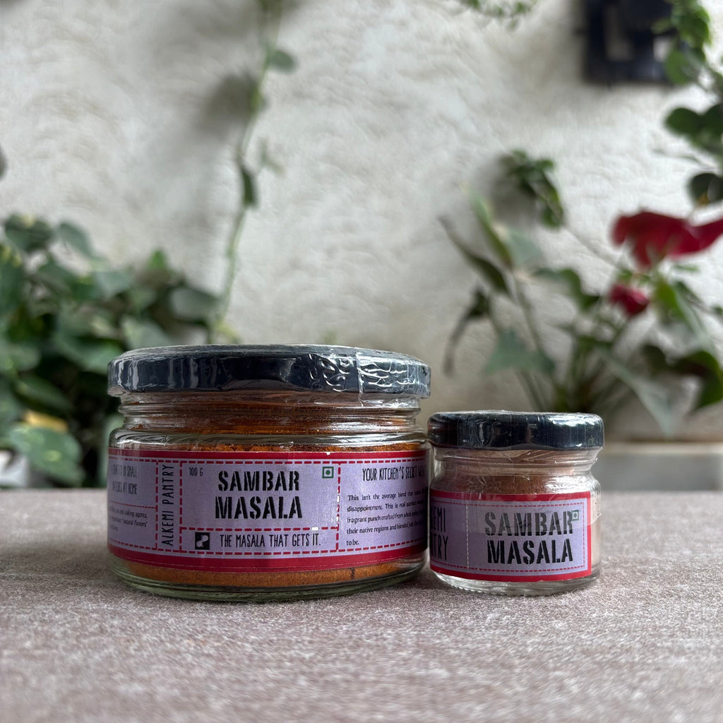 Two jars of Sambar Masala on a surface with a blurred background