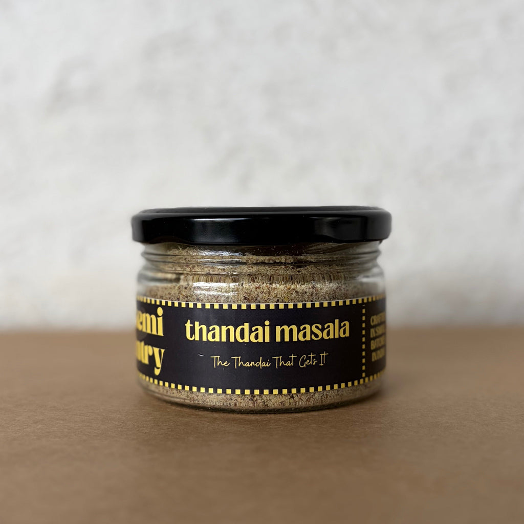 Jar of thandai masala on a textured surface with a neutral background
